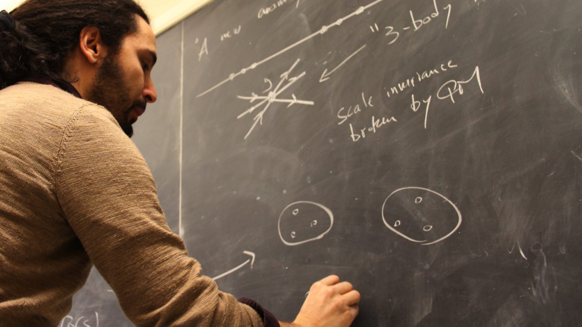 Professor writes on a black board.