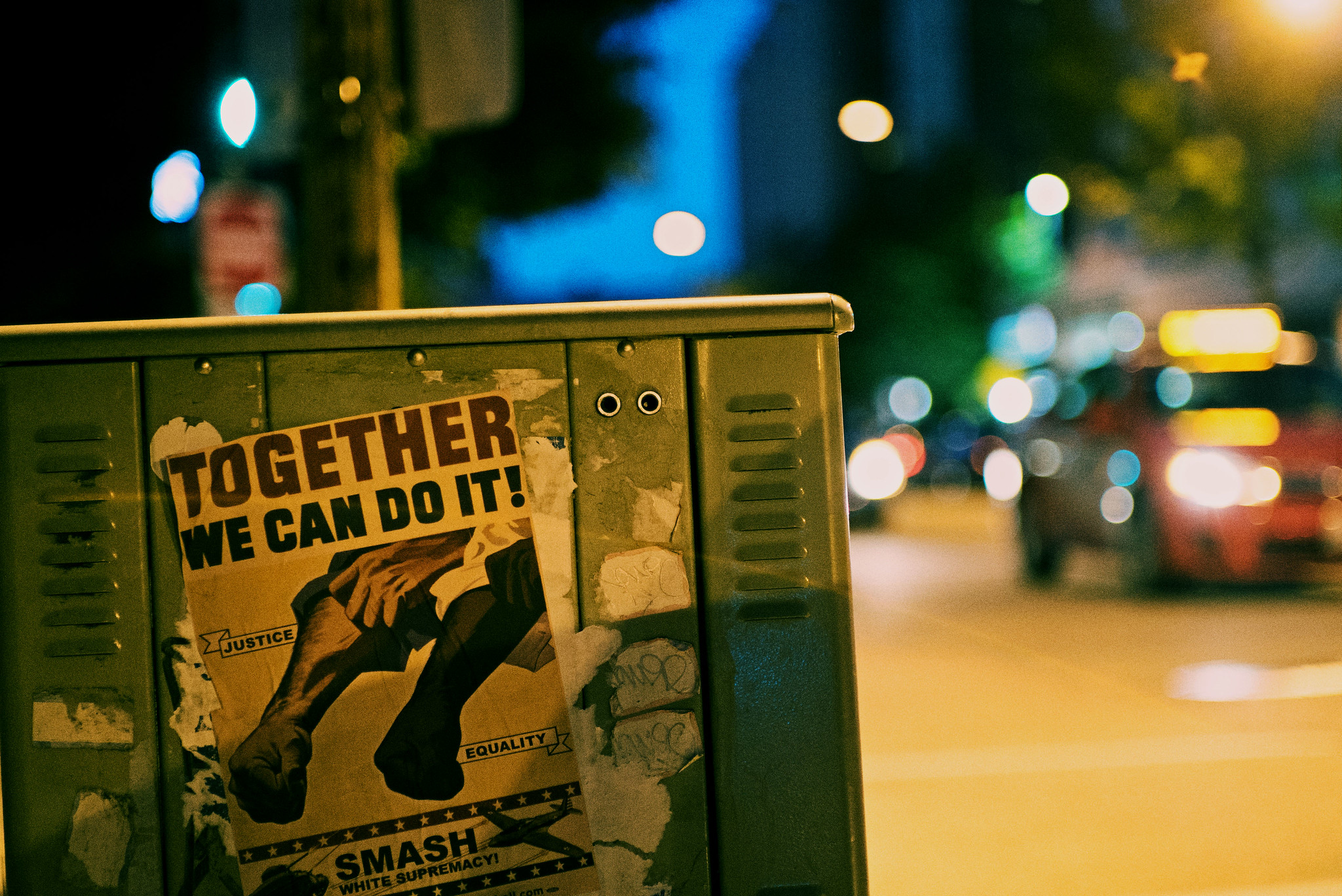 Night time photo of a technical box on a sidewalk with a Black Lives Matter poster that reads "Together, we can do it! Smash White Supremacy."