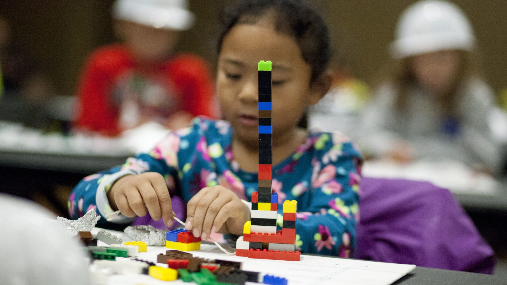 A little girl plays with legos at a table.