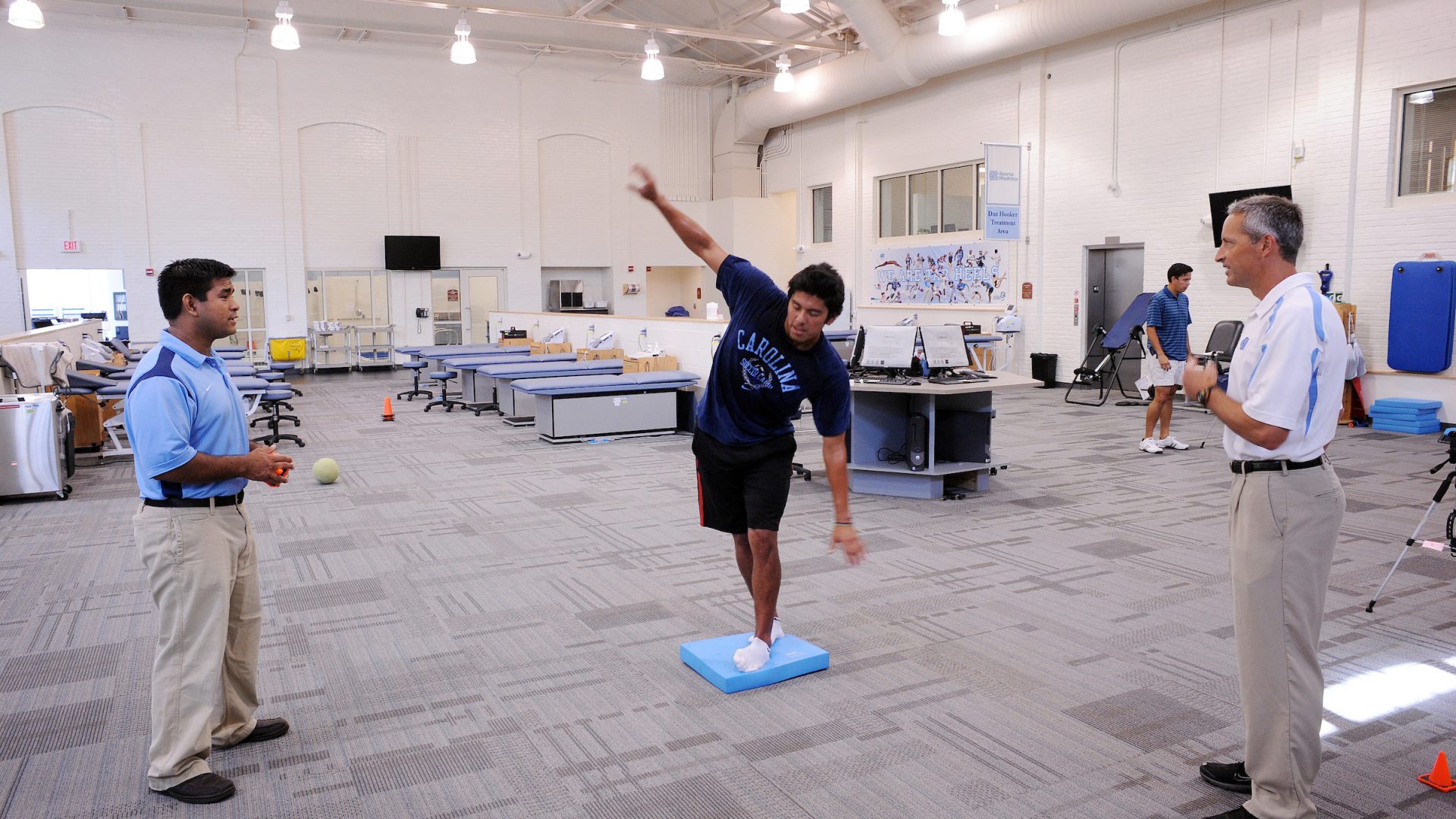 Researchers watch as a test subject balances on a small blue mat.