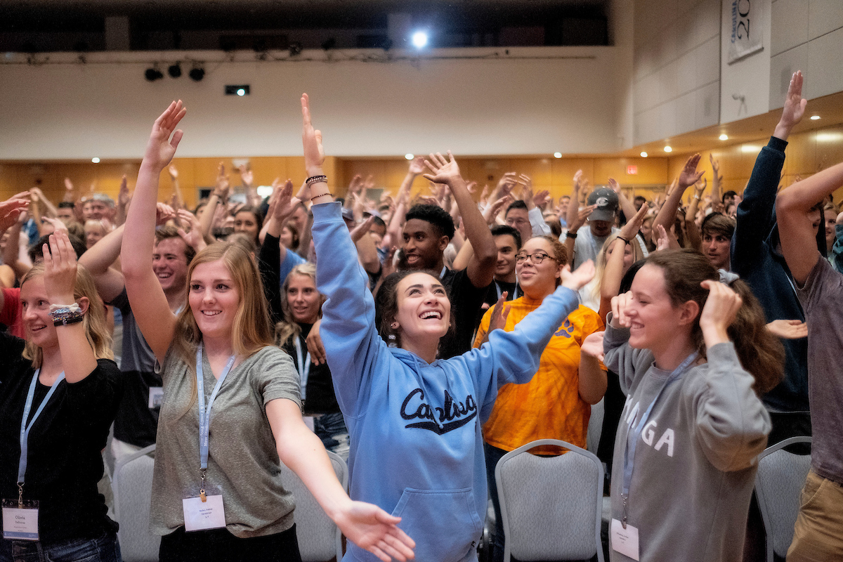 Students cheer in a large auditorium during UNC Orientation.