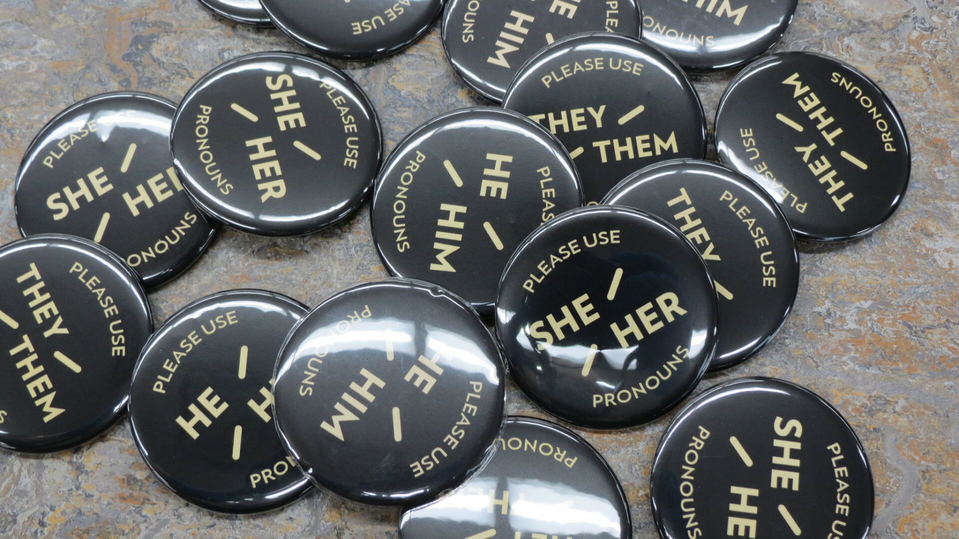 A pile of buttons with people's pronouns on them.