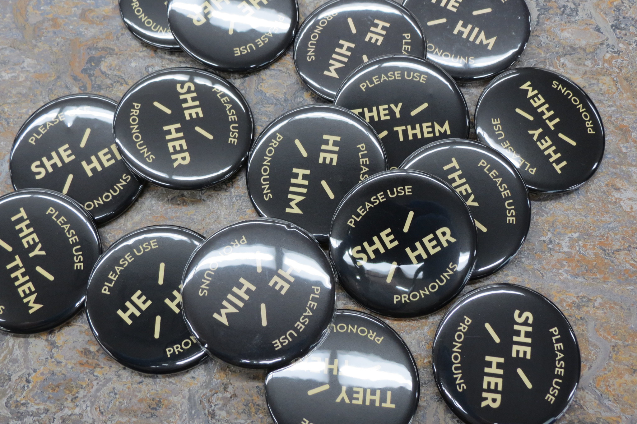 A pile of buttons with people's pronouns on them.