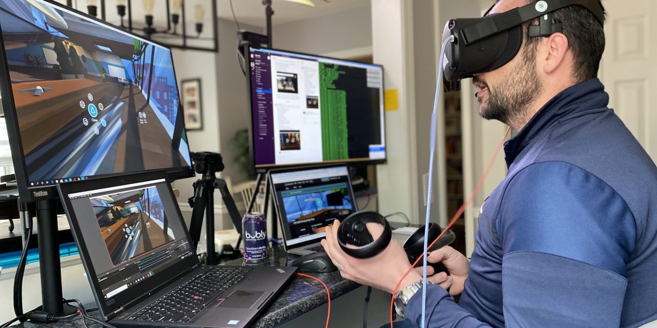 Steven King sits at a computer with a VR headset on. The screens show what he sees in the headset.