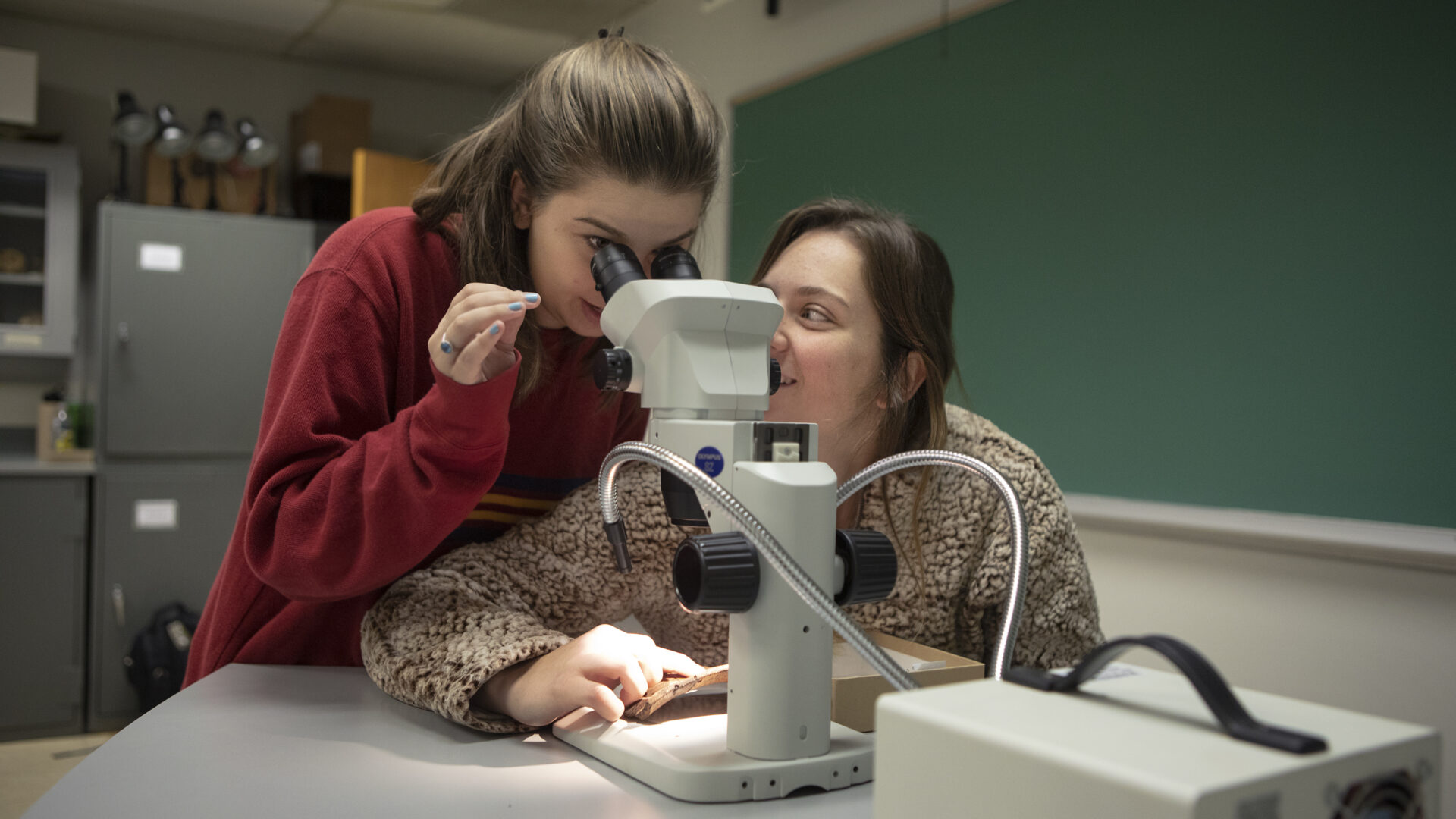 Two students look through a microscope.