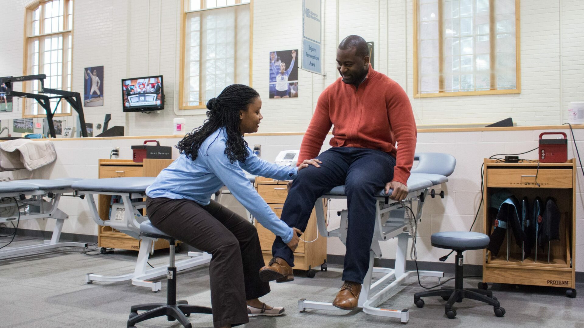 A researcher helps a patient with flexing their leg.