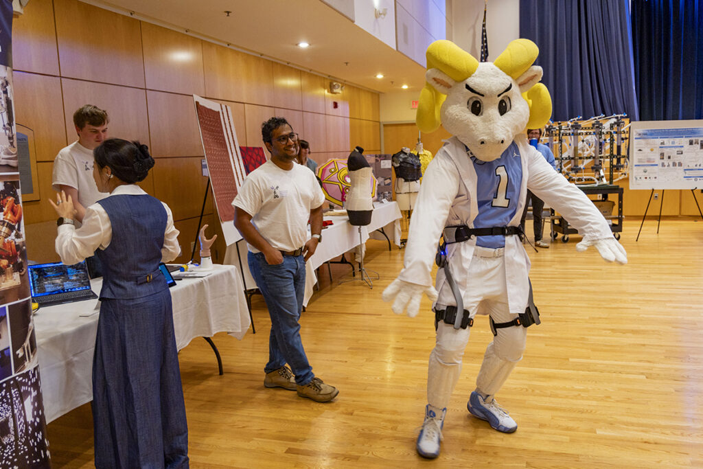 Shot of the Great Hall during the Research and Discovery fair. There are science booths set up with a number of people walking around.